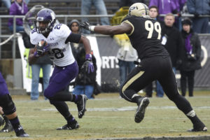 Nov 22, 2014; West Lafayette, IN, USA; Northwestern Wildcats running back Justin Jackson (28) runs past Purdue Boilermakers defensive end Ryan Russell (99) in the 2nd half at Ross Ade Stadium. Northwestern won the game 38-14.Mandatory Credit: Sandra Dukes-USA TODAY Sports
