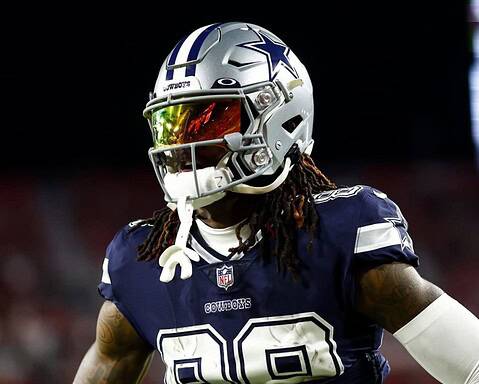 Football player in a Dallas Cowboys uniform and helmet stands on the field during a game.