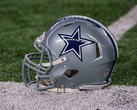 A silver football helmet with a blue star logo rests on the grass near a white line, hinting at the player who left it there.