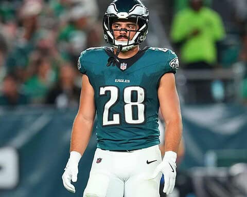 Young male football player in Philadelphia Eagles uniform with helmet during game, focusing on player action and team spirit.