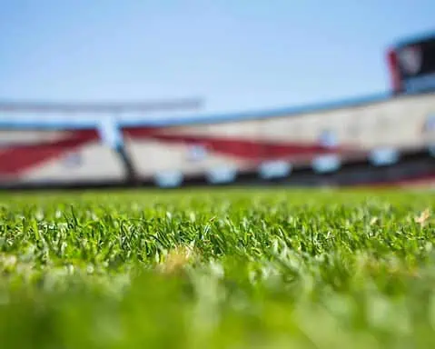 Lush green football field grass with stadium seating and scoreboard in the background, showcasing the Dallas Cowboys' AT&T Stadium, perfect for NFL fans and sports enthusiasts.