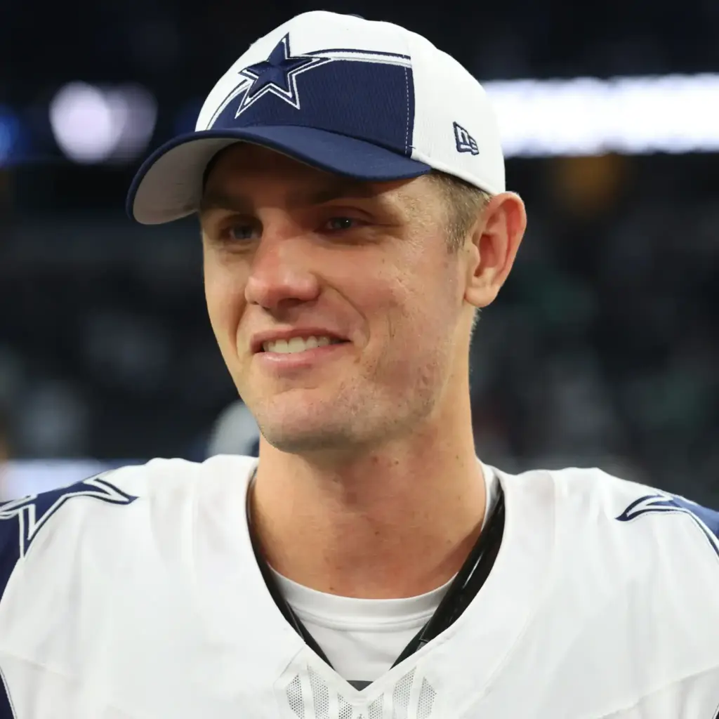 Young male Dallas Cowboys football player wearing team cap and jersey, smiling after game, inside the star stadium, NFL sports, athlete, sports photography.