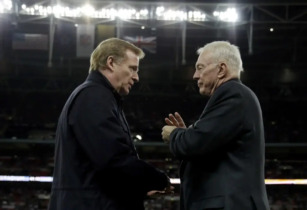 Supporting head coach and executive at AT&T Stadium, inside the Dallas Cowboys stadium, discussing strategy or game plans during a football game.