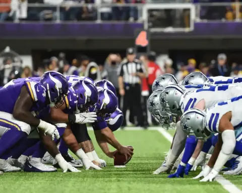 Rushing players from the Minnesota Vikings and Dallas Cowboys line up at the line of scrimmage during an NFL game, showcasing intense team rivalry and game strategy on the football field.