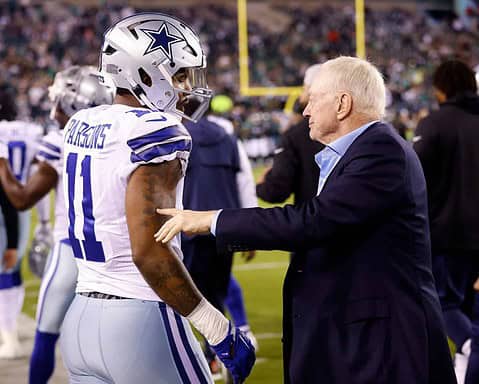 Dallas Cowboys player talking with coach on the sideline during an NFL game, showcasing team strategy and leadership.