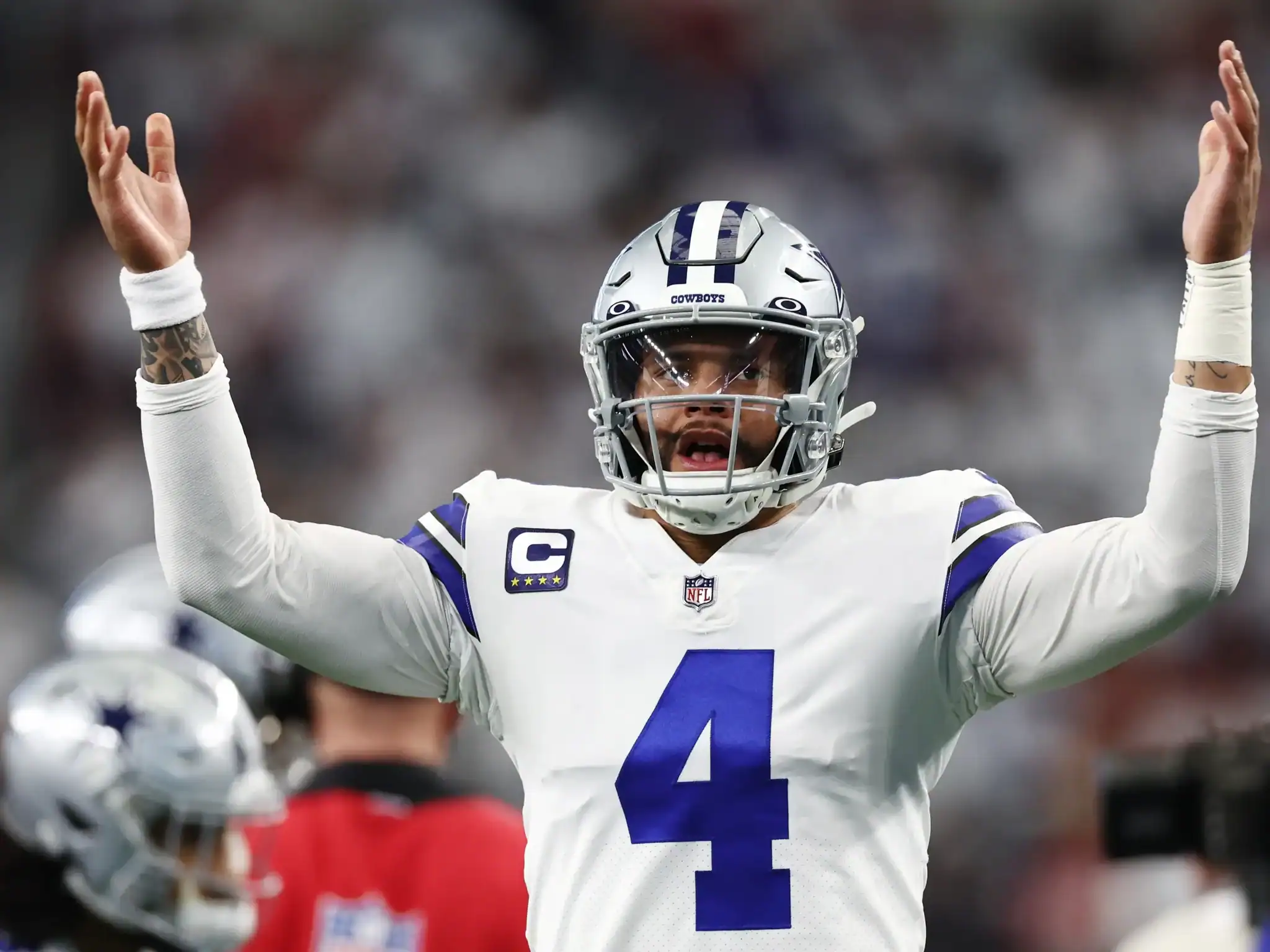 DeMarcus Lawrence, a Dallas Cowboys football player, celebrating on the field in his uniform with arms raised, analyzing game moments during NFL game action.