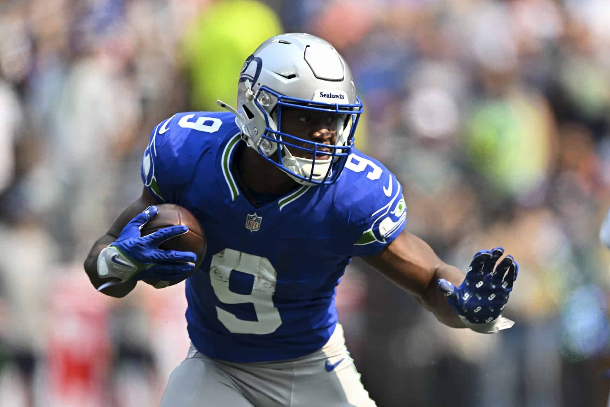 Running back in Seattle Seahawks uniform carrying football during game.