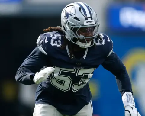 Dallas Cowboys player in action during a game, wearing helmet and dark jersey, focused on the play, symbolizing NFL sportsmanship and athleticism.