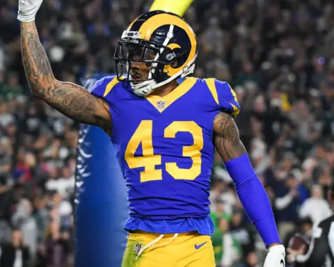 Rams football player wearing number 43 jersey celebrating on the field during a game, with a crowd and referee in the background, showcasing NFL action and team spirit.