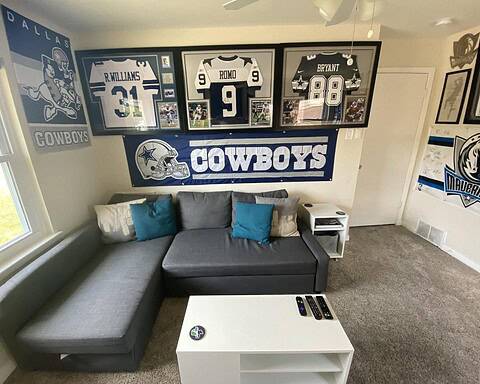 Dallas Cowboys memorabilia and decor featuring framed jerseys and team banners displayed in a sports-themed room.
