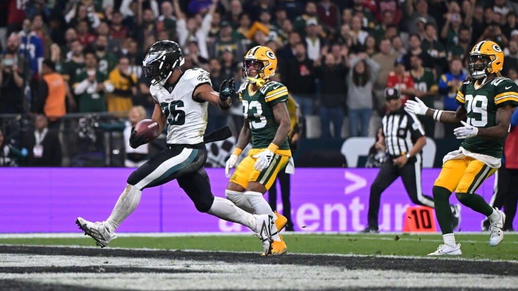 Running back with football in hand evading defenders during NFL game, Dallas Cowboys vs Green Bay Packers, inside the star football stadium.