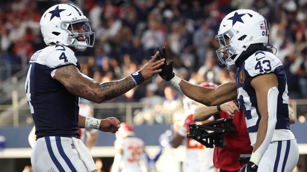 High-quality image of Dallas Cowboys players in football gear exchanging high-fives during a game, showcasing team spirit and on-field action.