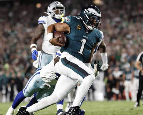 Running back with jersey number 1 carrying football, defensive players in background, game action, Philadelphia Eagles team, NFL football game, stadium crowd in background, inside the star.