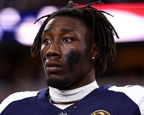 Injured Dallas Cowboys player wearing football uniform with black eye paint, close-up shot, showing a serious expression during a game at AT&T Stadium, insider coverage of Dallas Cowboys football team.