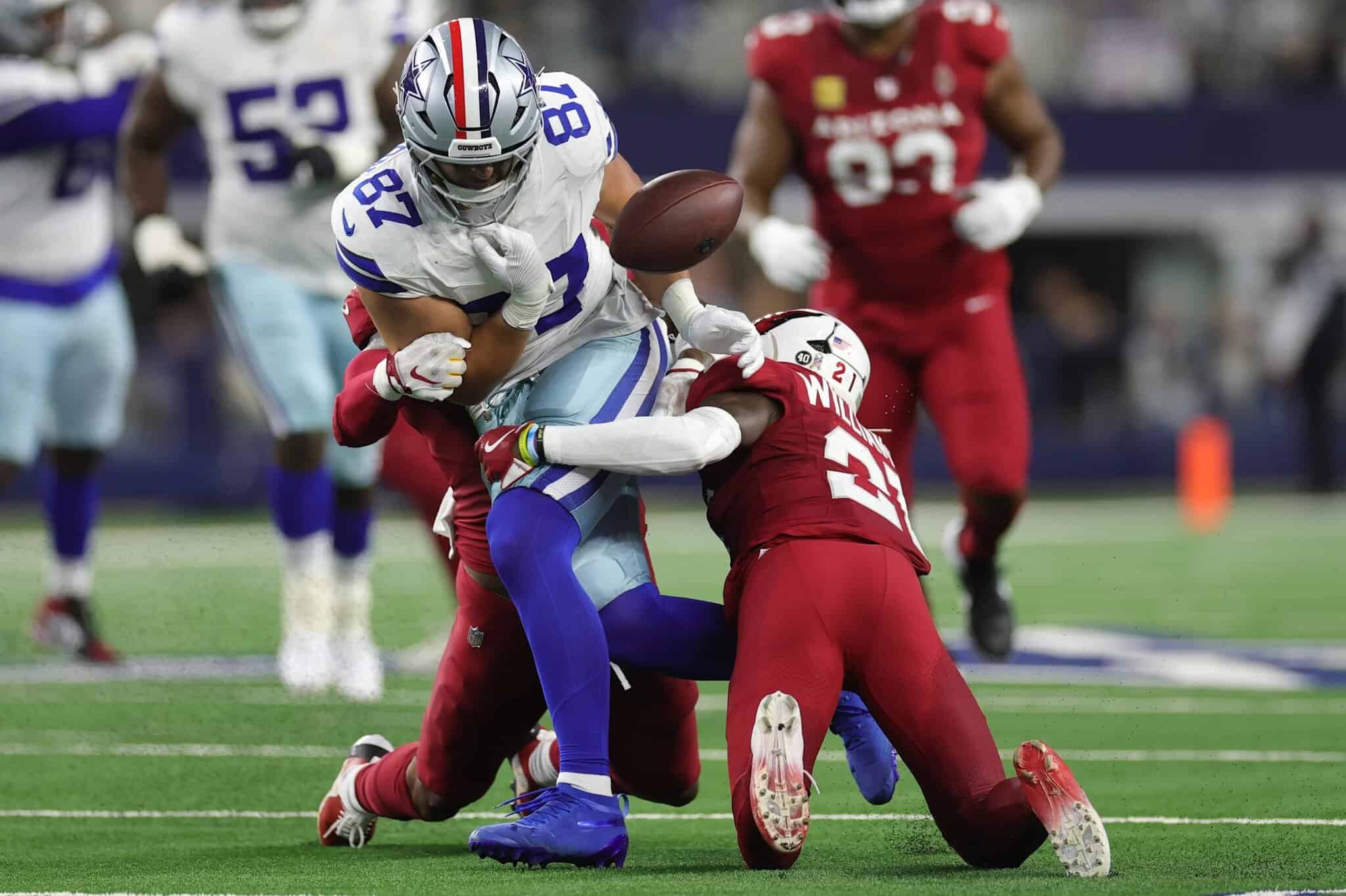 Dallas Cowboys player tackles Arizona Cardinals player during football game on field, showcasing intense NFL action and football sports competition.
