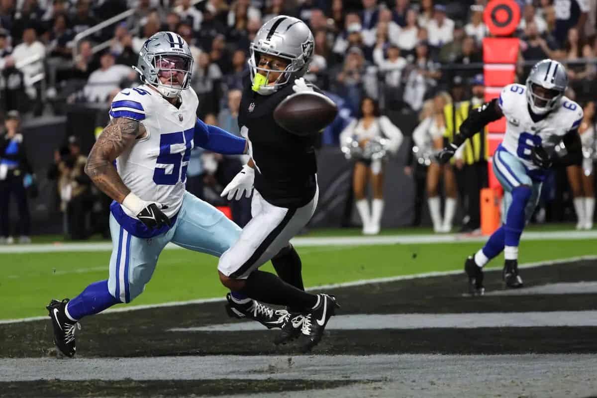 Evading a tackle during an NFL game between the Dallas Cowboys and the Las Vegas Raiders, showcasing athleticism and intense competition on the football field.