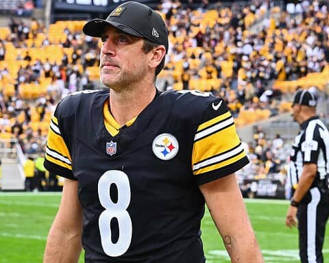 Close-up of Tom Brady in a Steelers uniform on the football field, highlighting his focused expression amidst the crowd, emphasizing sports passion and NFL action.