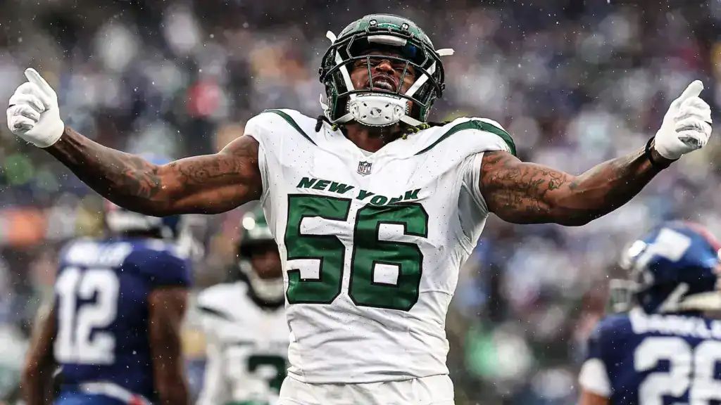 New York Jets linebacker wearing a white jersey with number 56 celebrates with arms extended during a game in snowy conditions.