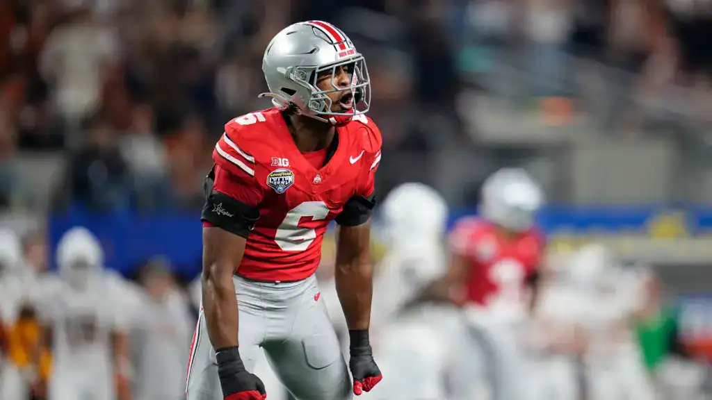 Ohio State Buckeyes 2026 NFL Draft prospect wearing a red No. 2 jersey yells pre-snap during a high-energy college football game, displaying leadership and emotion on defense.