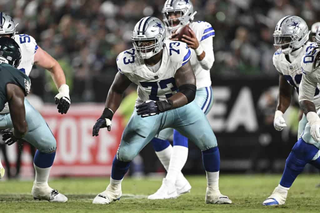 Dallas Cowboys offensive lineman wearing a white No. 73 jersey blocks at the line of scrimmage during an NFL game. 