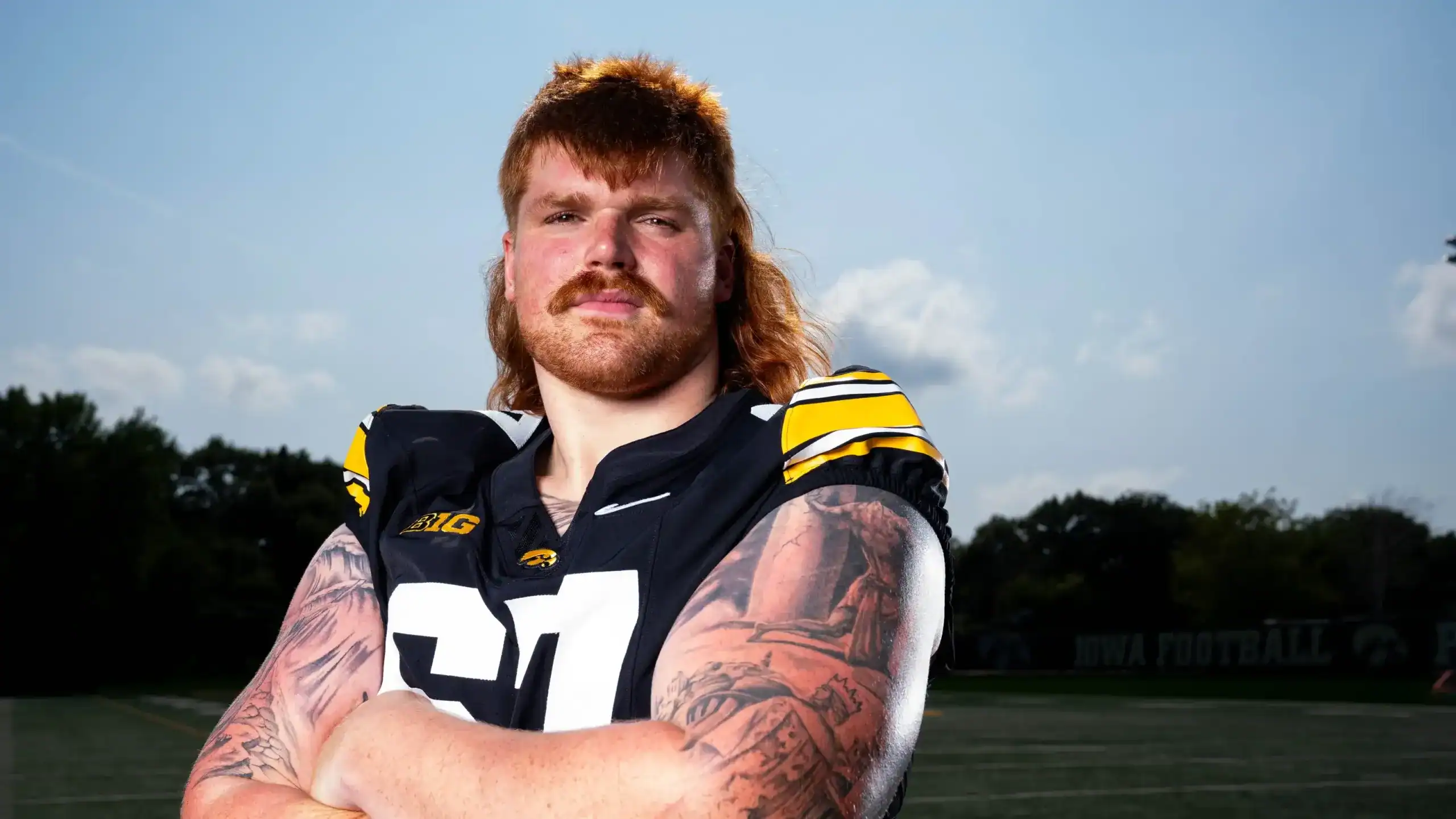 Iowa Hawkeyes offensive lineman stands with arms crossed during a portrait session, highlighted as a Senior Bowl prospect ahead of the NFL Draft.