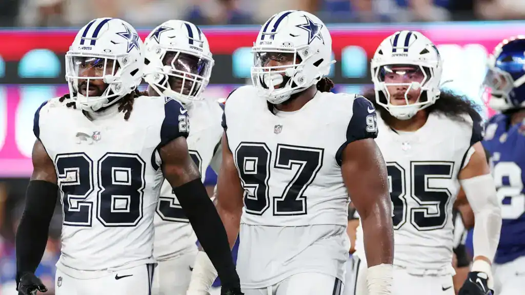 Dallas Cowboys defense taking the field together in white uniforms, representing toughness, depth, and physical identity