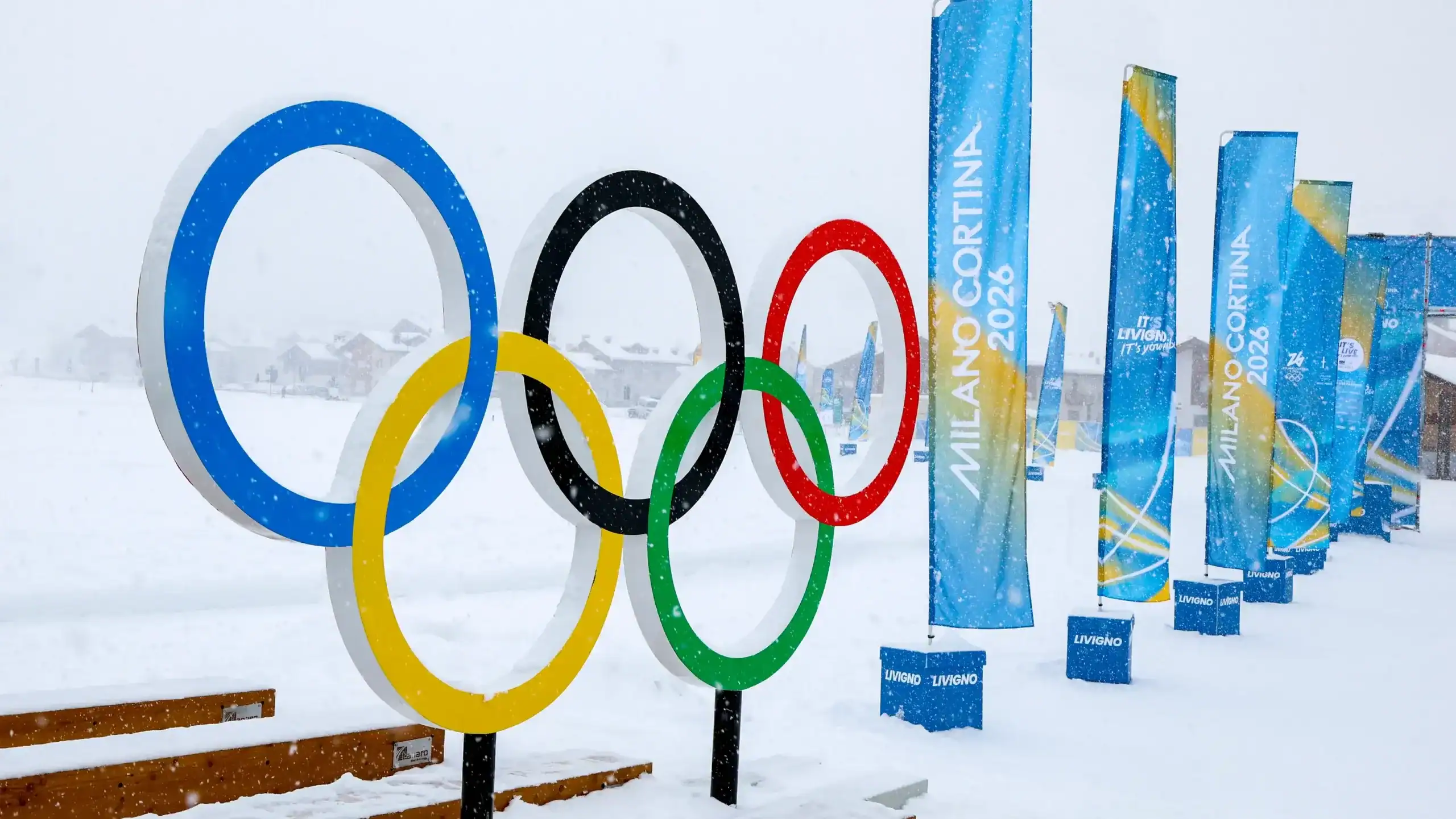 Winter Olympics 2026 Olympic rings displayed in snowy Livigno, Italy with Milano Cortina banners in the background
