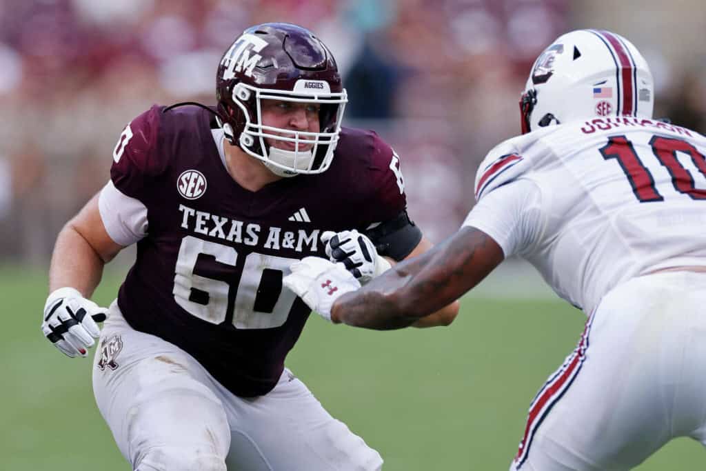 Texas A&M Aggies offensive lineman wearing a maroon No. 60 jersey blocks at the line of scrimmage, highlighted in an NFL draft evaluation of interior linemen.