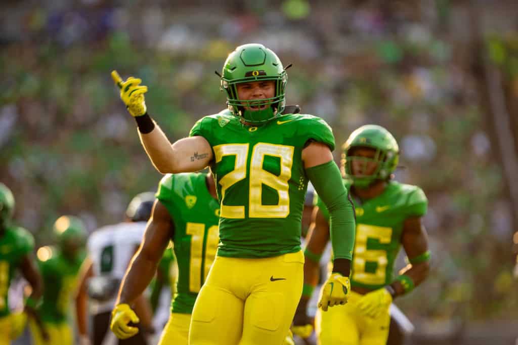 Oregon Ducks line backer wearing a green No. 28 jersey celebrates on the field, featured in an NFL draft discussion of versatile defensive prospects.
