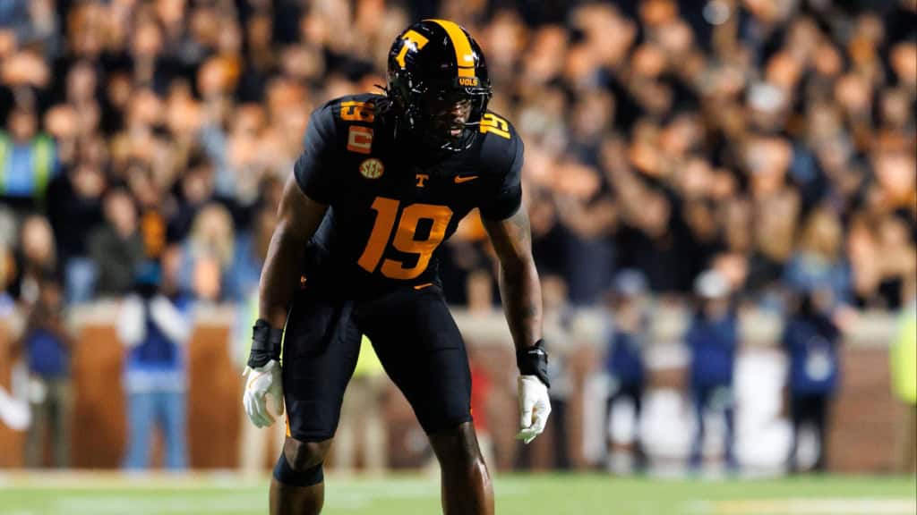 Joshua Josephs (#19) in a black Tennessee Volunteers uniform crouched in a defensive stance before the snap, focused and ready as the stadium crowd blurs in the background at Neyland Stadium.