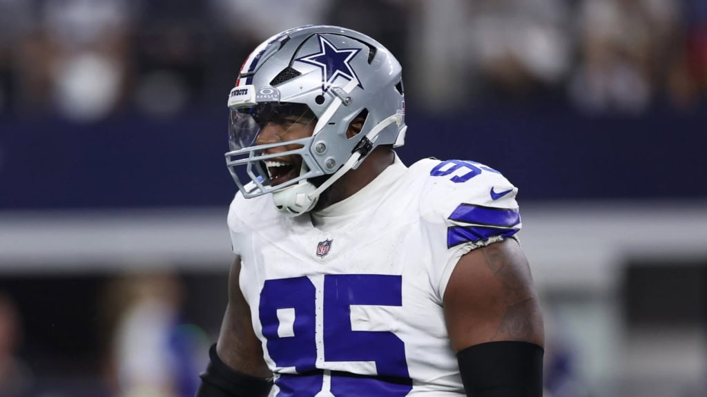 Kenny Clark celebrates during a Dallas Cowboys game, wearing a white jersey with number 95 and silver helmet with the star logo.