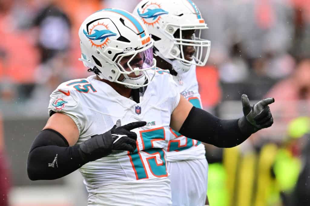 Jaelan Phillips in a Miami Dolphins white uniform pointing during an NFL game action shot.