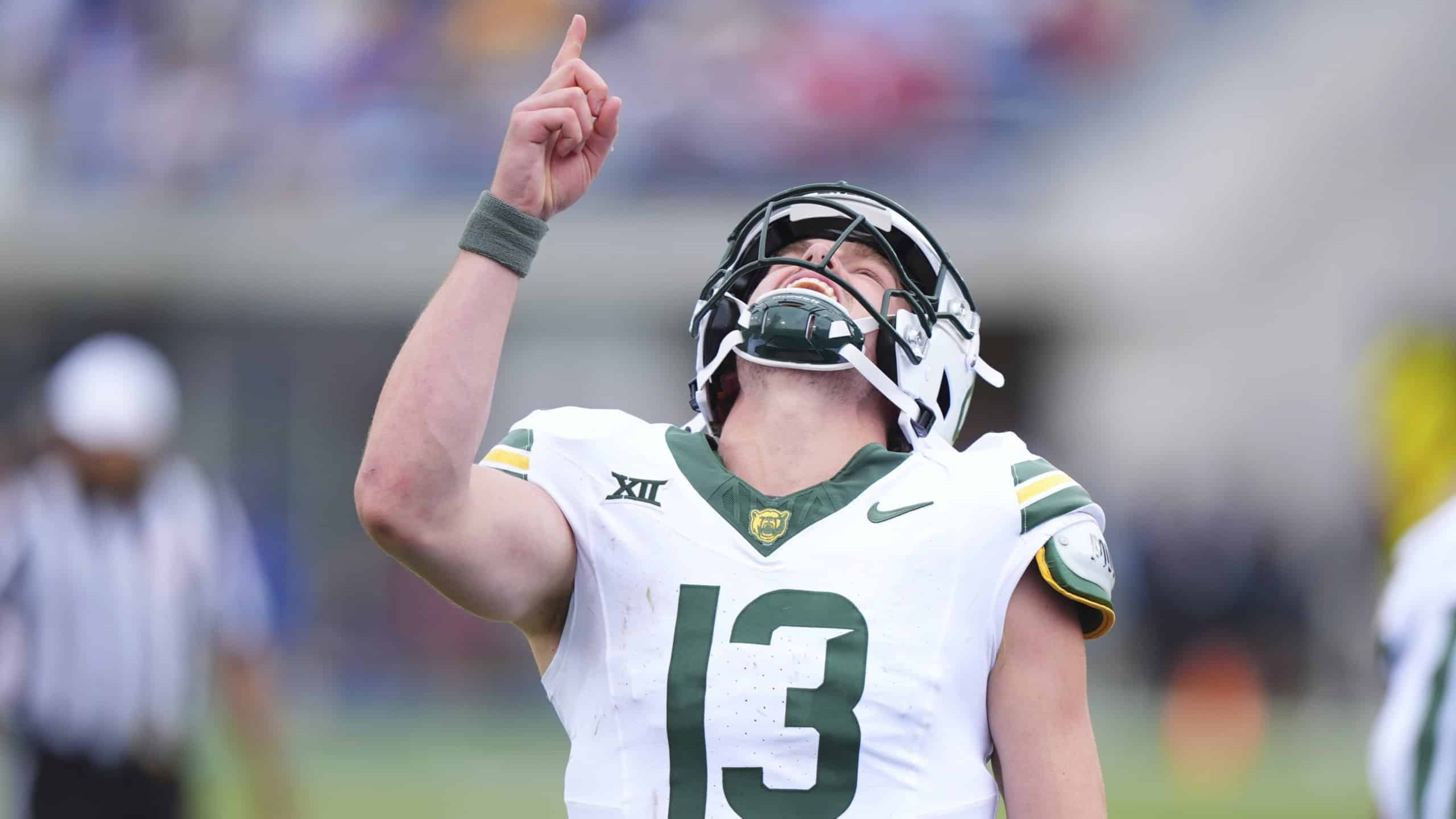 Baylor Bears quarterback #13 celebrates on the field, pointing upward after a big play while wearing a white and green uniform.