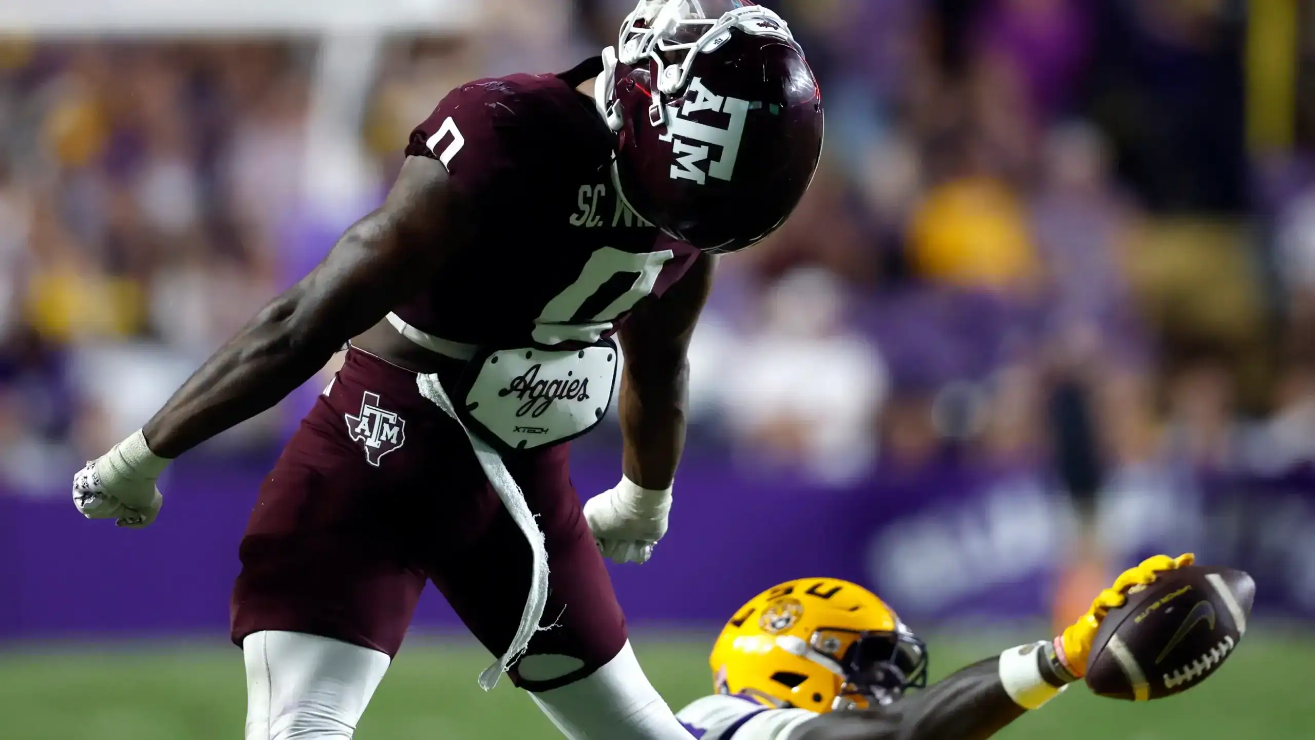 Scooby Williams celebrating a big defensive play for Texas A&M, standing over a loose football during a high-energy SEC game.