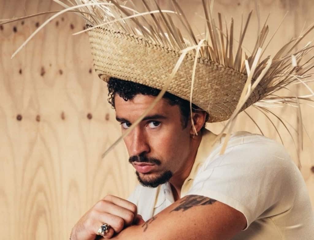 Bad Bunny photographed ahead of his Super Bowl halftime show, wearing a straw hat and neutral-toned outfit