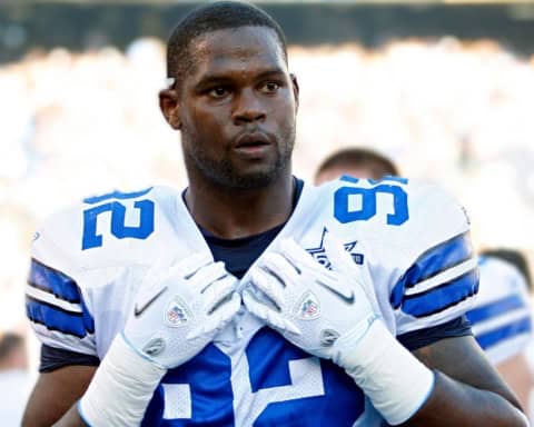 Marcus Dixon in a Dallas Cowboys uniform wearing number 92, adjusting his gloves before an NFL game.