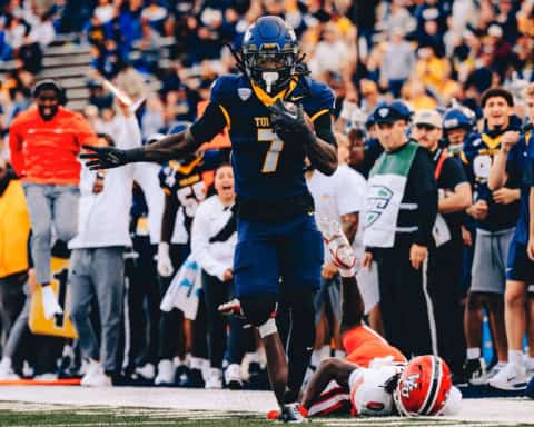 Emmanuel McNeil-Warren sprinting down the sideline in a Toledo Rockets uniform after making a big defensive play.