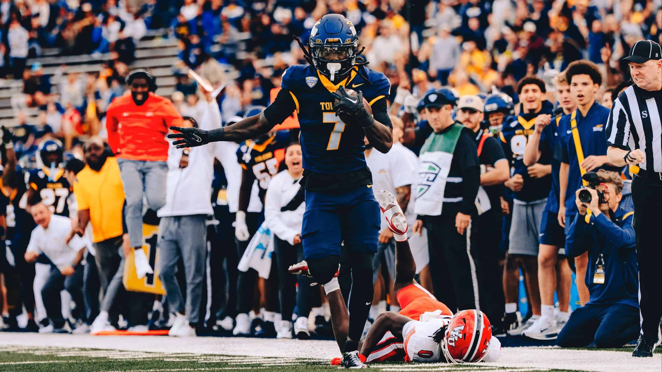 Emmanuel McNeil-Warren sprinting down the sideline in a Toledo Rockets uniform after making a big defensive play.
