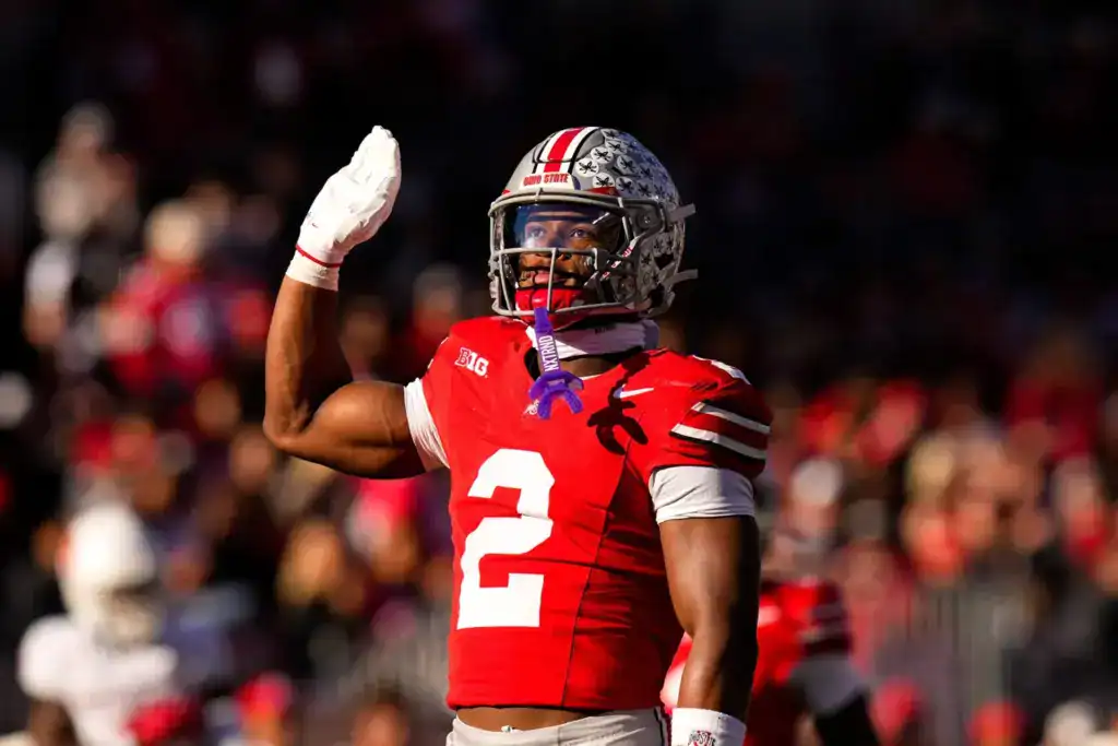 Ohio State safety Caleb Downs raises his hand during a game while wearing a red Buckeyes uniform