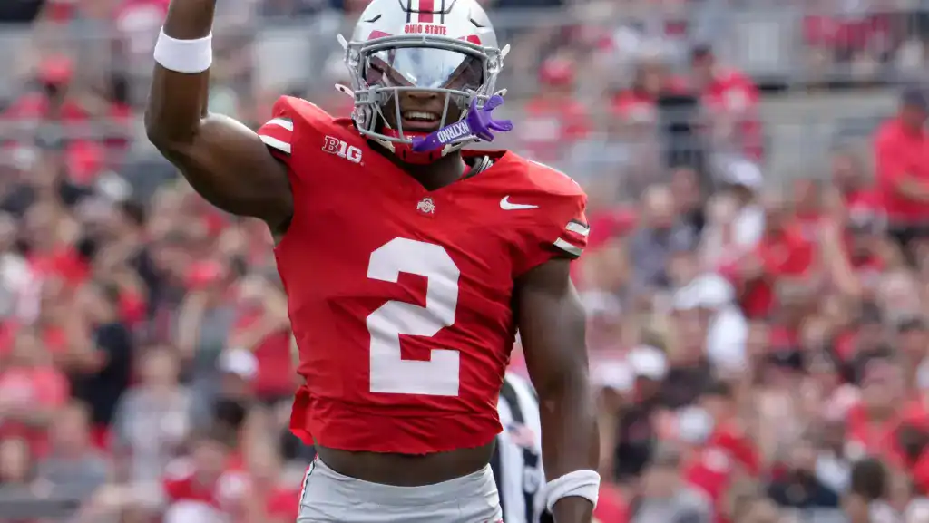 Ohio State safety Caleb Downs celebrates on the field in a red jersey during a college football game