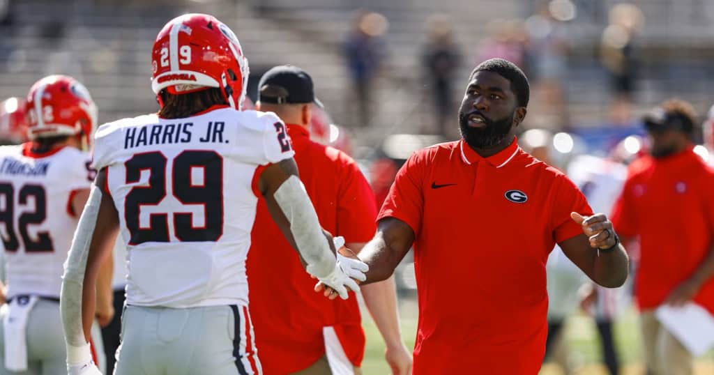 Georgia Bulldogs defensive coach greeting a player during warmups on the sideline before a college football game.