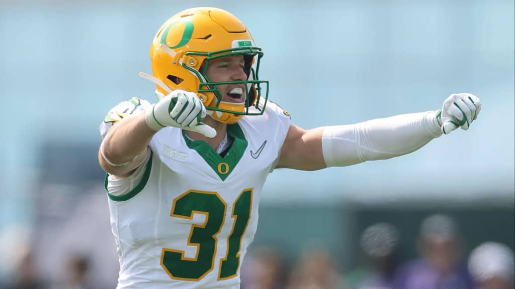 Oregon defensive back wearing No. 31 points and communicates coverage before the snap during a college football game, featured in a 2026 NFL Mock Draft projection.