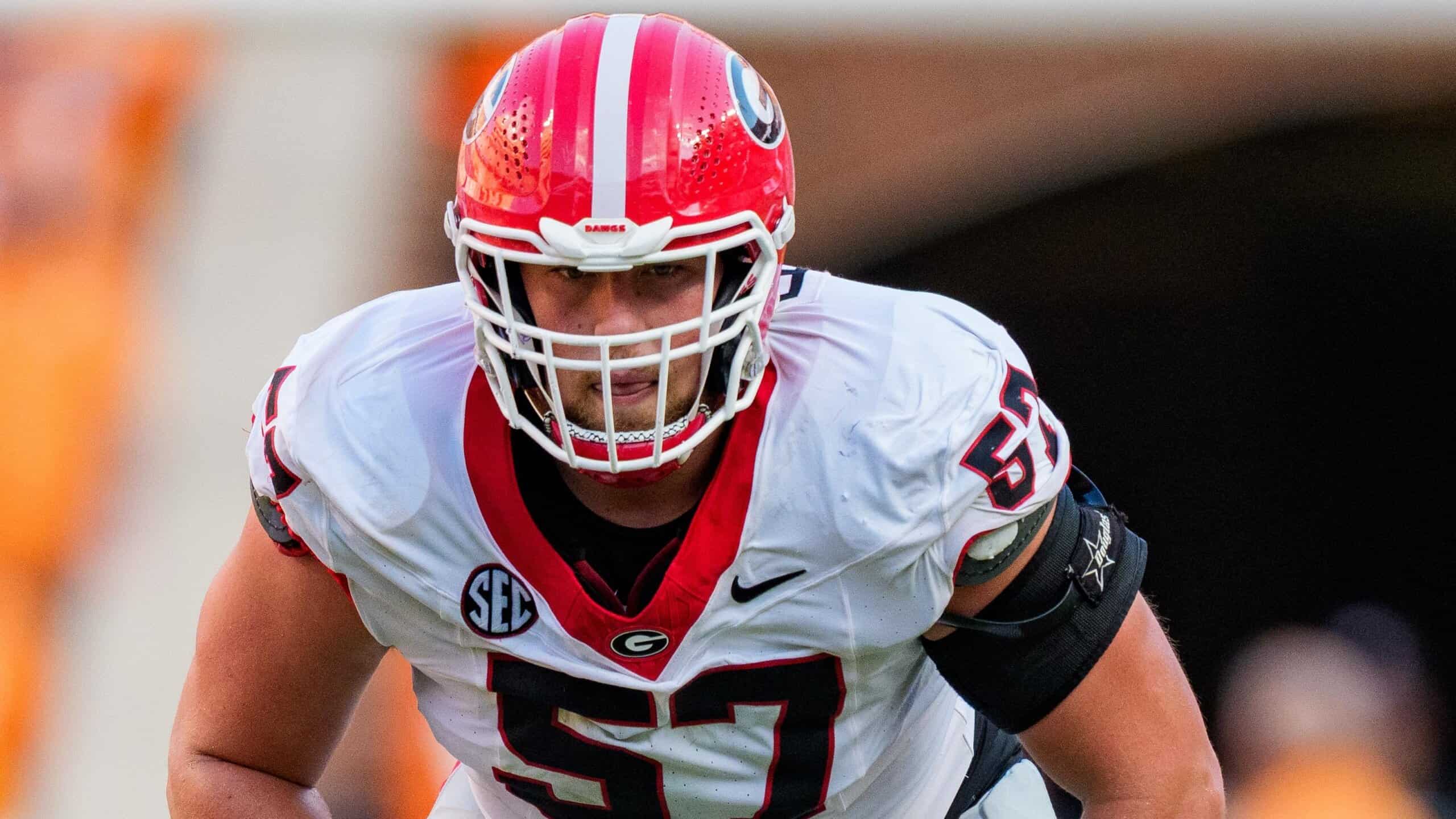 Georgia offensive lineman #57 in white uniform set at the line of scrimmage before the snap during an SEC football game