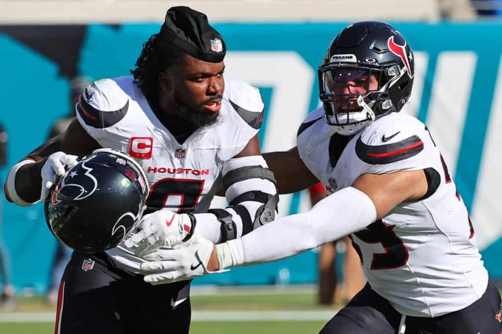 Houston Texans linebacker Azeez Al-Shaair being held back by a teammate during an NFL game.