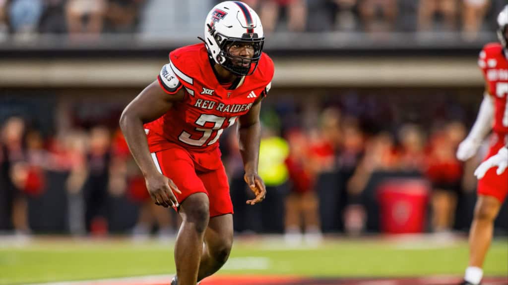 Texas Tech edge rusher David Bailey crouches in a red Red Raiders uniform before the snap during a college football game, highlighting a top 2026 NFL Draft prospect.