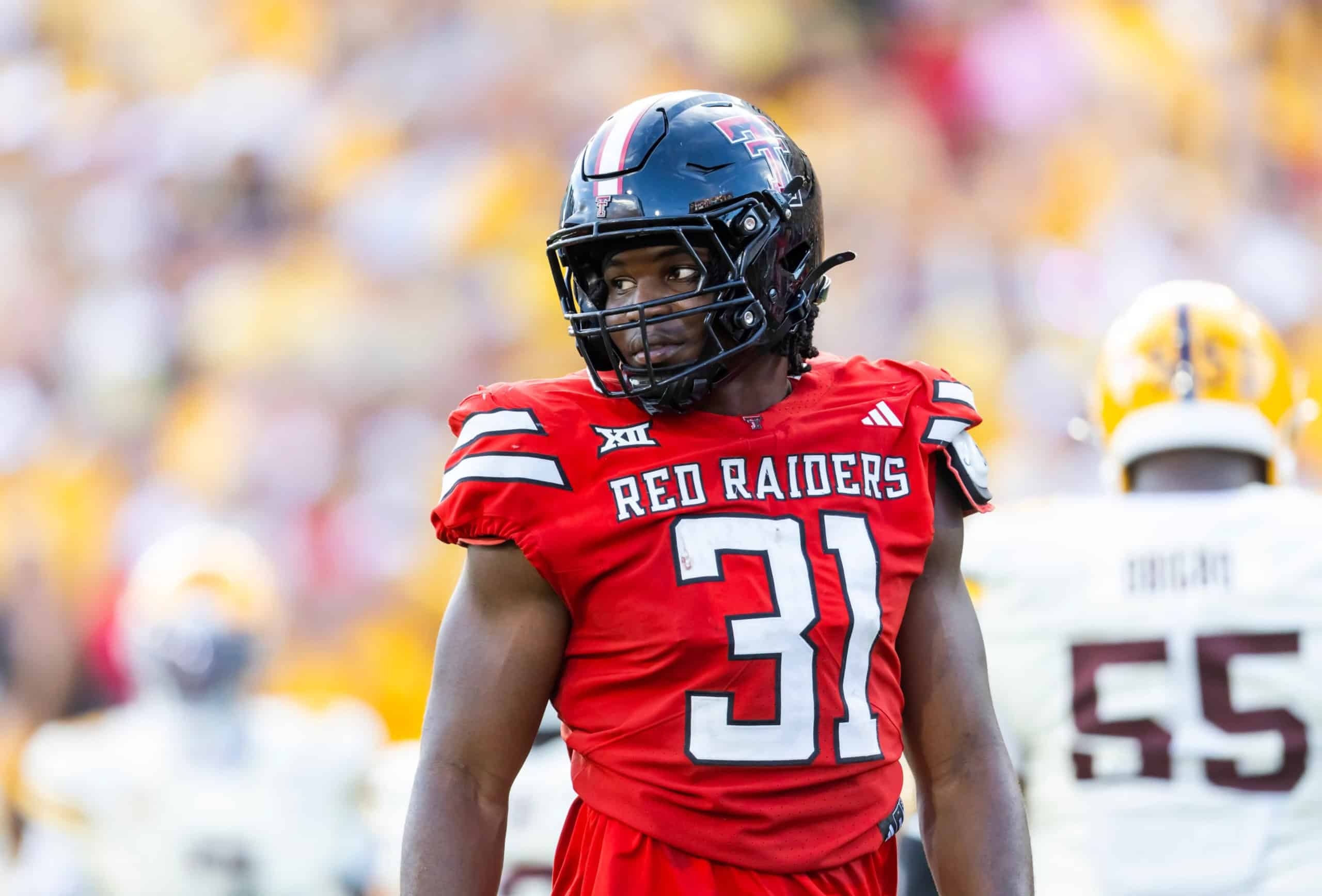 Texas Tech edge rusher David Bailey stands on the field in a red Red Raiders uniform between plays, showcasing one of the top 2026 NFL Draft prospects to watch.
