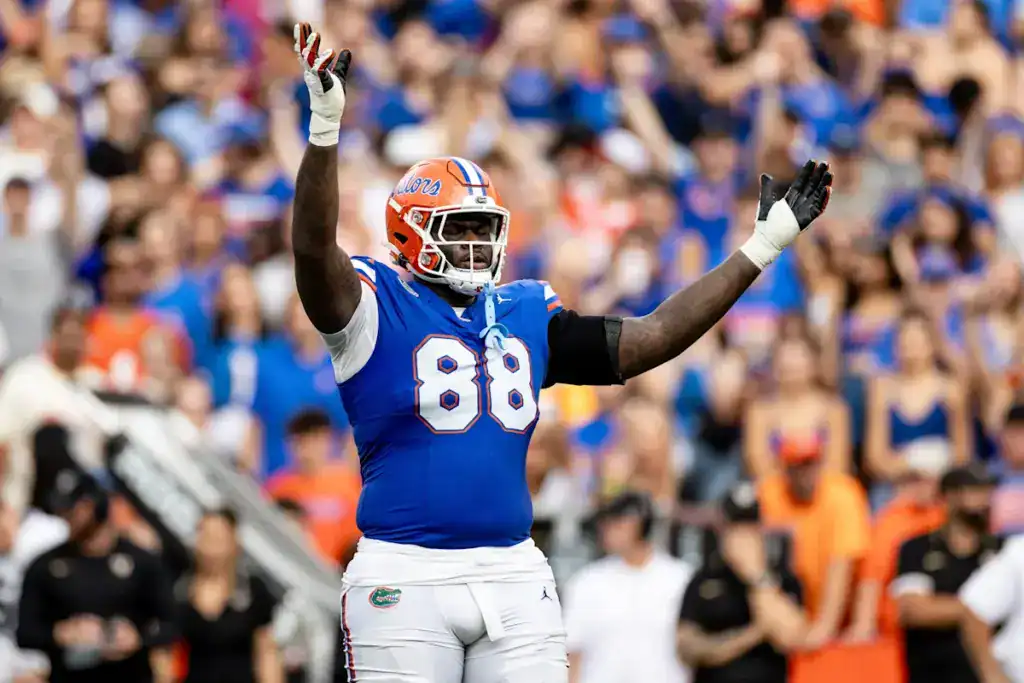 Caleb Banks, Florida draft prospect, raising both arms in celebration in a blue Gators uniform.