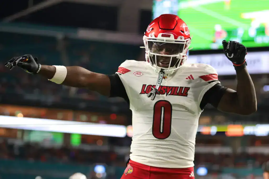 2026 NFL Draft prospect Chris Bell celebrates in Louisville’s white road uniform during a game.