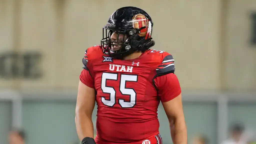 Spencer Fano, Utah offensive lineman and 2026 NFL Draft prospect, stands on the field in a red Utes uniform during game action.