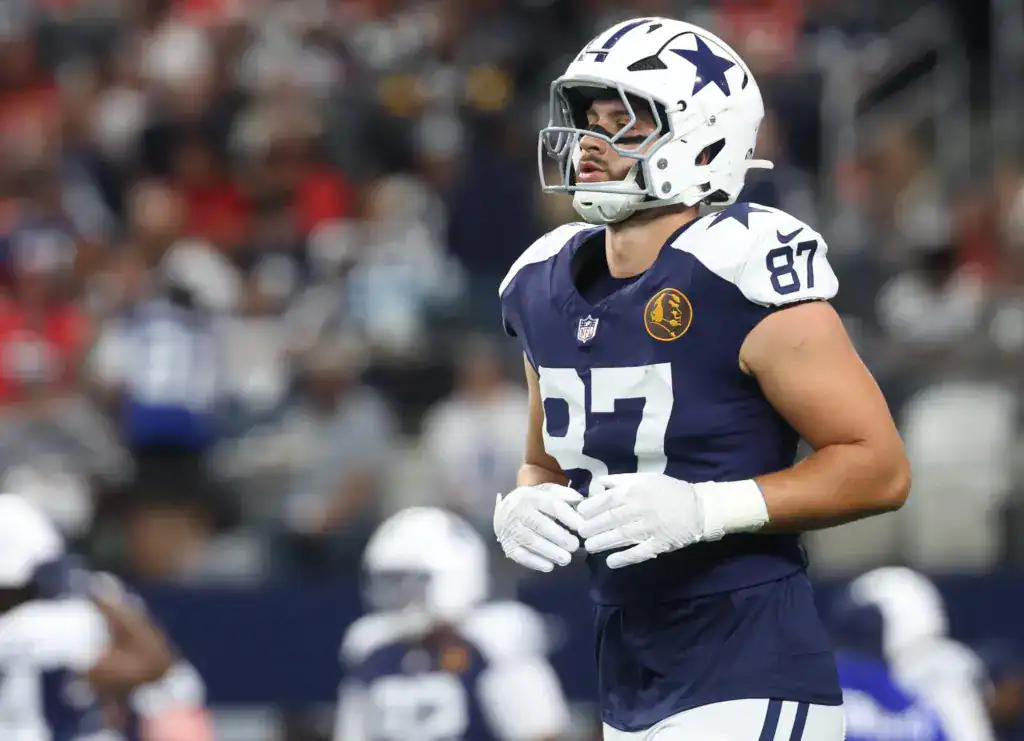 Dallas Cowboys tight end Jake Ferguson jogging on the field in his navy Cowboys uniform, featured as part of the 2026 Offensive Depth Chart projection.